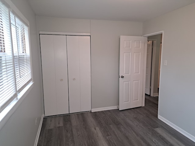 unfurnished bedroom with a closet and dark wood-type flooring