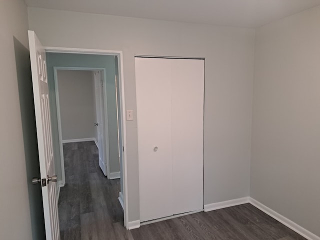 unfurnished bedroom with a closet and dark wood-type flooring