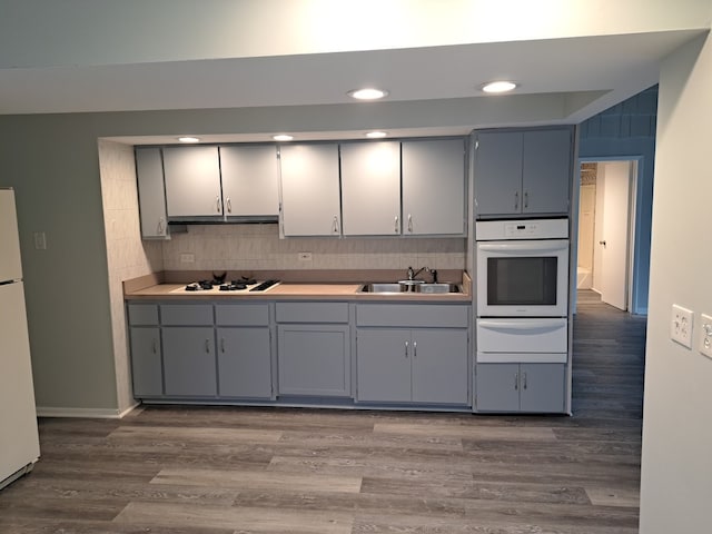 kitchen with sink, white appliances, tasteful backsplash, gray cabinets, and dark hardwood / wood-style flooring