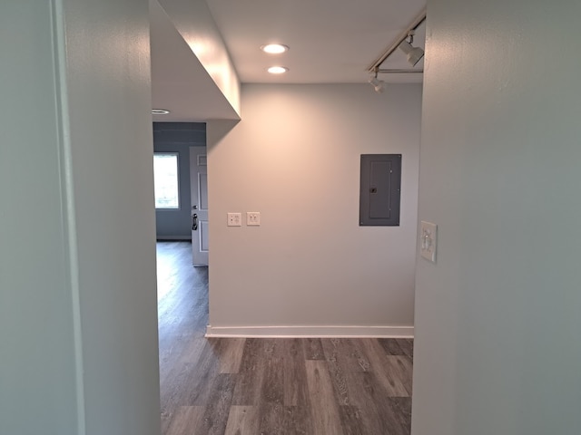 corridor featuring rail lighting, electric panel, and dark wood-type flooring