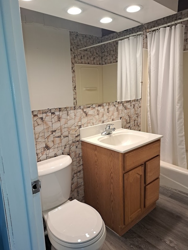 full bathroom featuring tile walls, shower / bath combo, wood-type flooring, vanity, and toilet