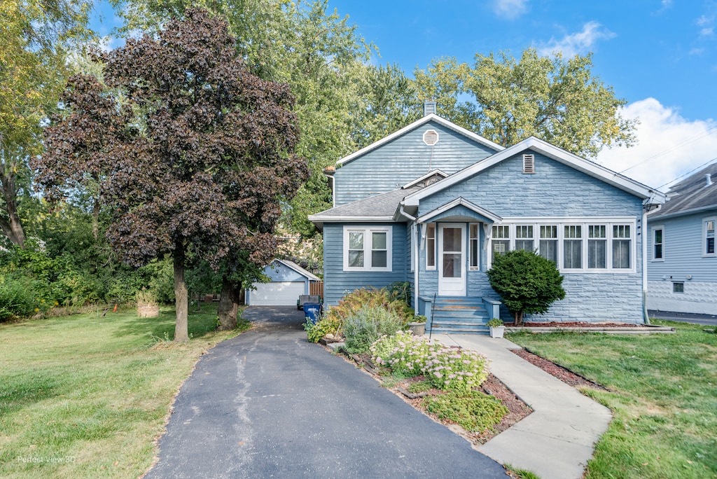 view of front of house with a front yard, a garage, and an outdoor structure