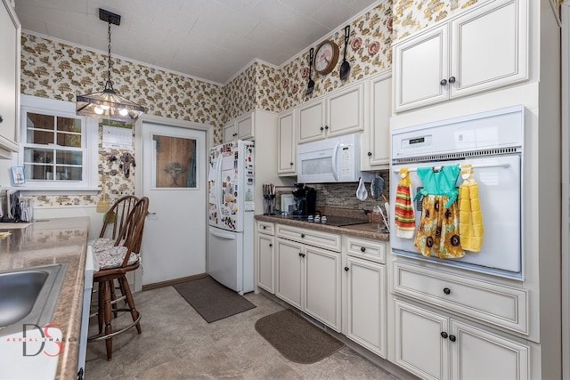 kitchen with hanging light fixtures, white appliances, white cabinetry, and sink