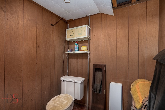 bathroom with vaulted ceiling, wooden walls, and toilet