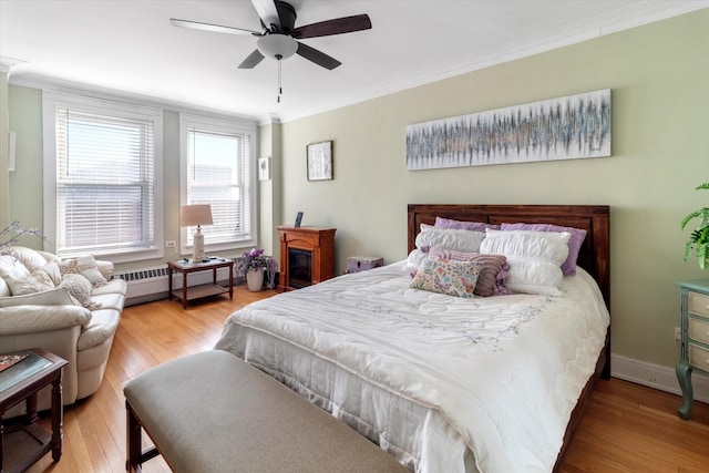 bedroom featuring crown molding, a baseboard radiator, ceiling fan, and hardwood / wood-style flooring