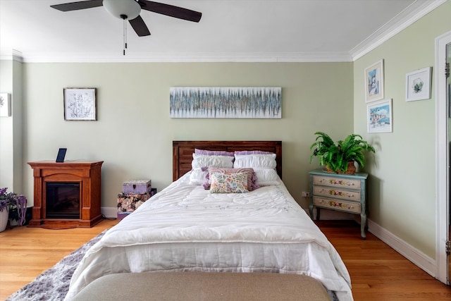 bedroom with ornamental molding, wood-type flooring, and ceiling fan