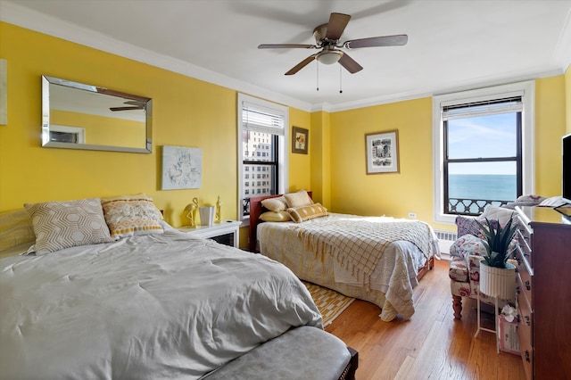 bedroom with light wood-type flooring, ornamental molding, and ceiling fan