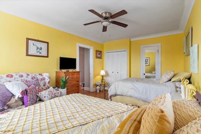 bedroom featuring hardwood / wood-style flooring, ornamental molding, ceiling fan, and a closet