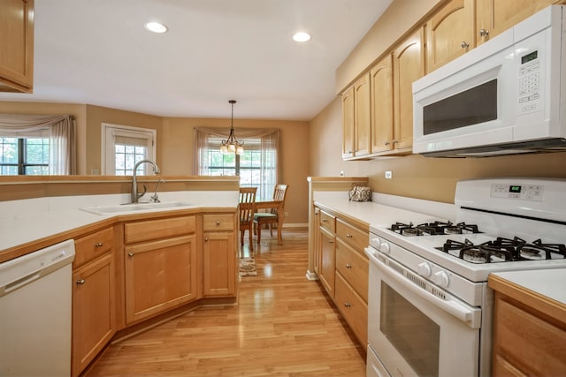 kitchen with pendant lighting, sink, white appliances, a notable chandelier, and light wood-type flooring