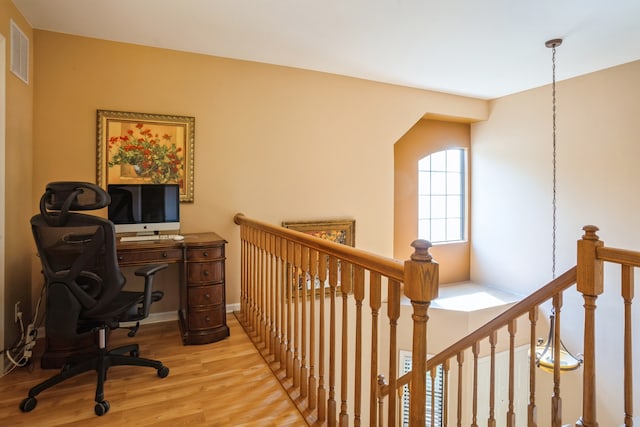 office with light hardwood / wood-style flooring and an inviting chandelier