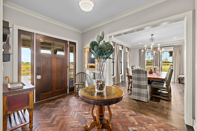 foyer with ornamental molding, a chandelier, and dark parquet flooring