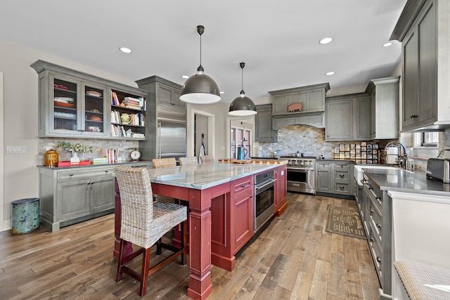 kitchen with hardwood / wood-style flooring, appliances with stainless steel finishes, a center island, and hanging light fixtures