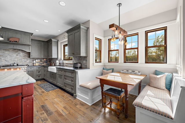 kitchen featuring gray cabinets, pendant lighting, high end stove, and dark hardwood / wood-style flooring