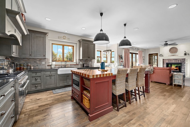 kitchen featuring decorative backsplash, hanging light fixtures, stainless steel appliances, and light hardwood / wood-style floors