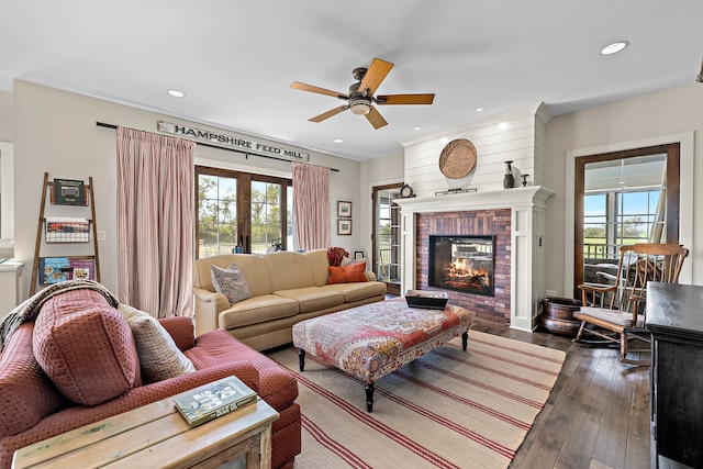 living room with ceiling fan, a healthy amount of sunlight, a fireplace, and dark hardwood / wood-style floors