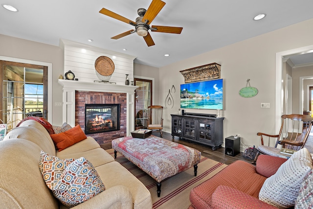 living room featuring ceiling fan, hardwood / wood-style flooring, ornamental molding, and a fireplace