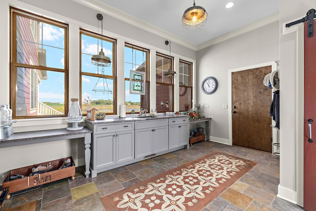 kitchen with ornamental molding, sink, a barn door, and decorative light fixtures