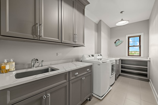 laundry room featuring light tile patterned flooring, cabinets, sink, and washer and clothes dryer