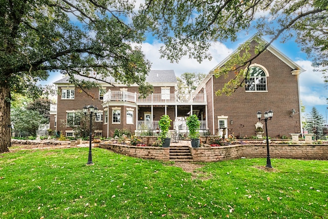 rear view of house with a balcony and a yard