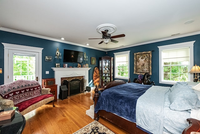 bedroom featuring ceiling fan, wood-type flooring, crown molding, and multiple windows