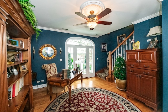 living area with crown molding, light hardwood / wood-style floors, and ceiling fan