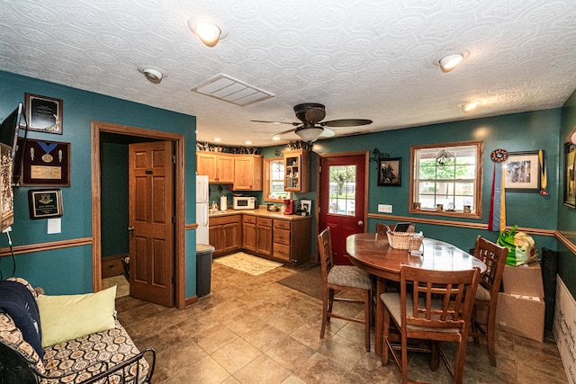 dining area featuring ceiling fan and a textured ceiling