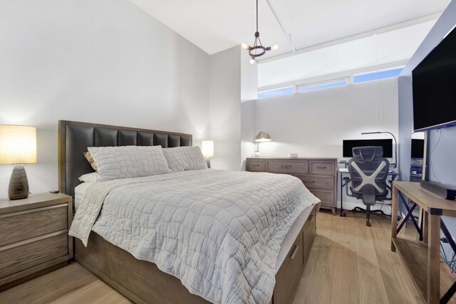 bedroom featuring an inviting chandelier and light hardwood / wood-style floors