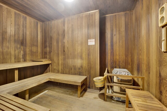 view of sauna / steam room with wood ceiling, wood-type flooring, and wooden walls