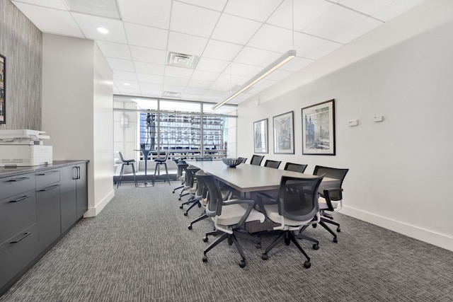 carpeted dining space featuring expansive windows and a drop ceiling