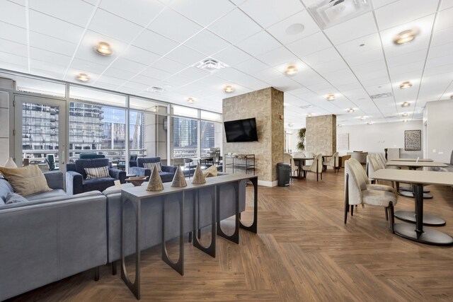 living room with floor to ceiling windows, parquet floors, and a large fireplace