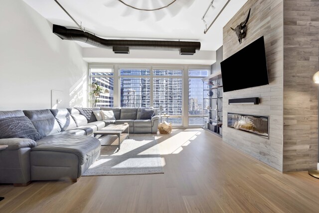 living room with wooden walls, a large fireplace, and hardwood / wood-style flooring