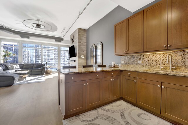 kitchen featuring backsplash, kitchen peninsula, sink, and light hardwood / wood-style flooring