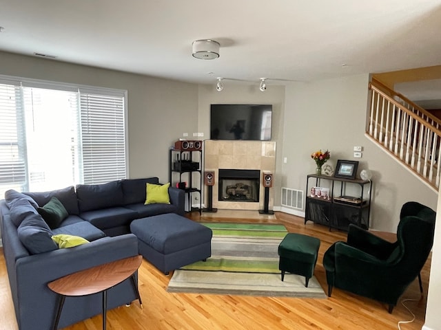 living room featuring a tile fireplace and wood-type flooring