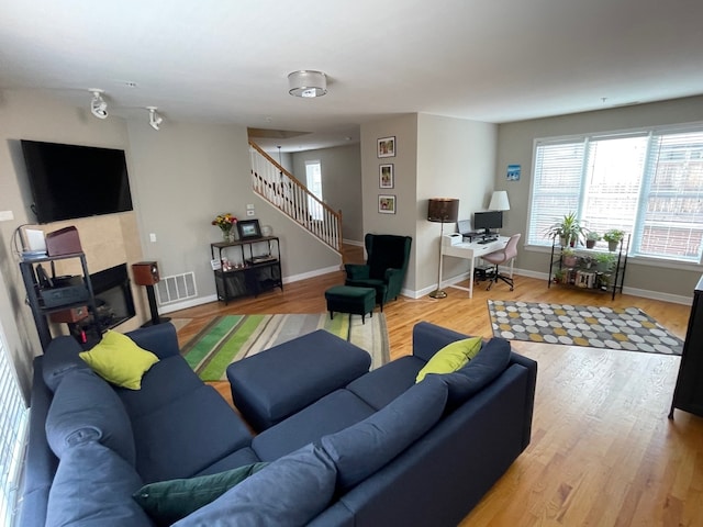 living room with wood-type flooring and a tiled fireplace