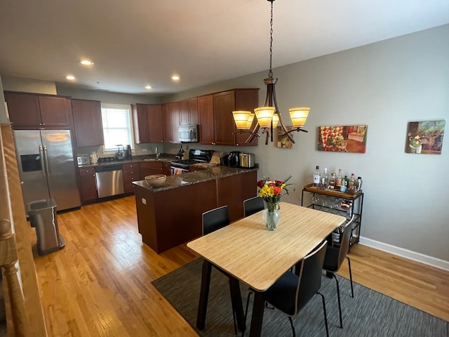 dining space with light hardwood / wood-style floors and an inviting chandelier