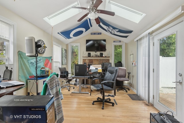 home office featuring ceiling fan, hardwood / wood-style flooring, and vaulted ceiling with skylight