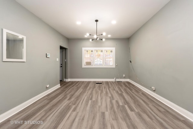 unfurnished dining area featuring a chandelier and light wood-type flooring