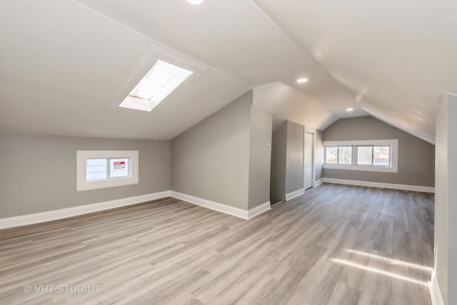 bonus room featuring lofted ceiling with skylight and light hardwood / wood-style flooring