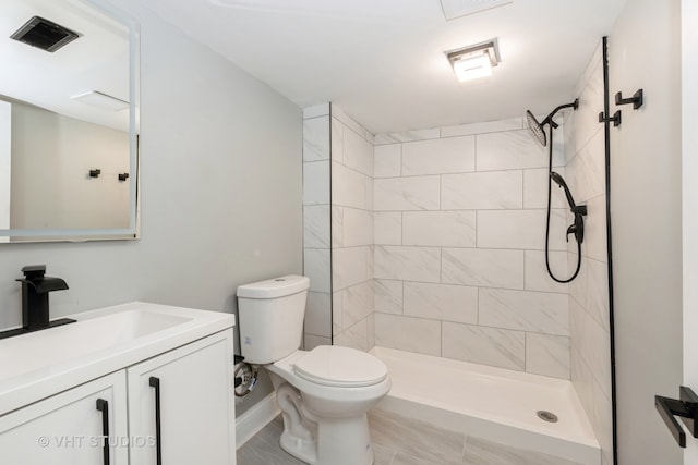 bathroom featuring toilet, vanity, and a tile shower