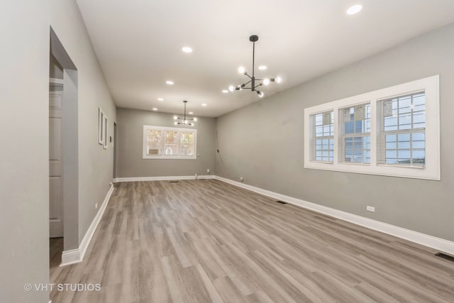 empty room with light hardwood / wood-style floors and a chandelier