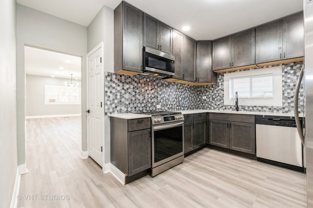 kitchen with dark brown cabinetry, light hardwood / wood-style flooring, appliances with stainless steel finishes, and sink