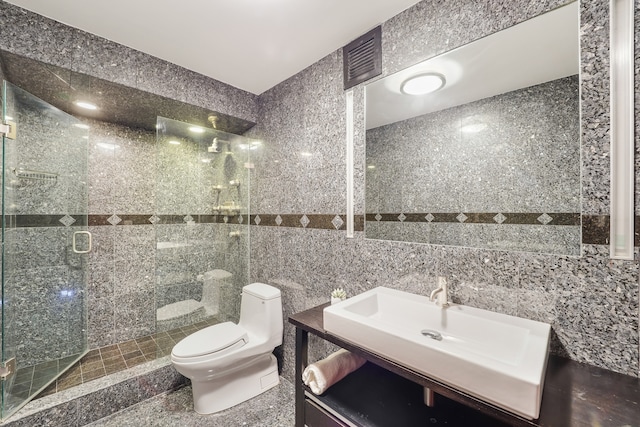 bathroom with tile walls, vanity, toilet, and an enclosed shower