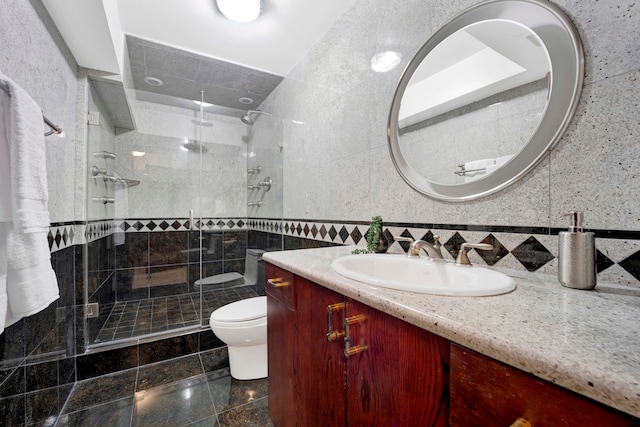 bathroom featuring tile walls, a shower with door, vanity, and toilet