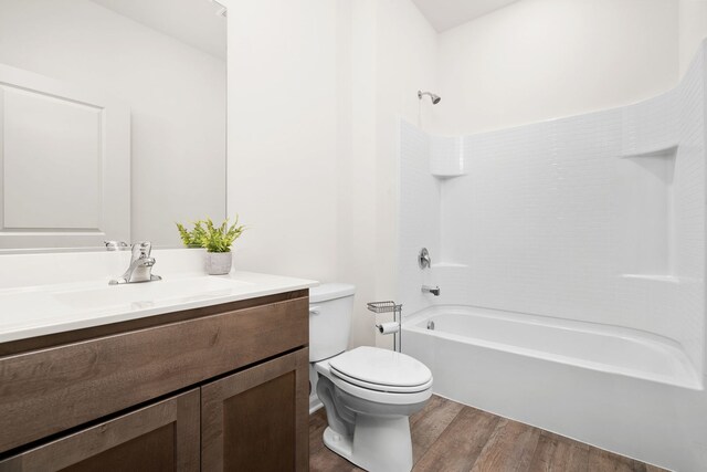 full bathroom featuring wood-type flooring, shower / washtub combination, vanity, and toilet