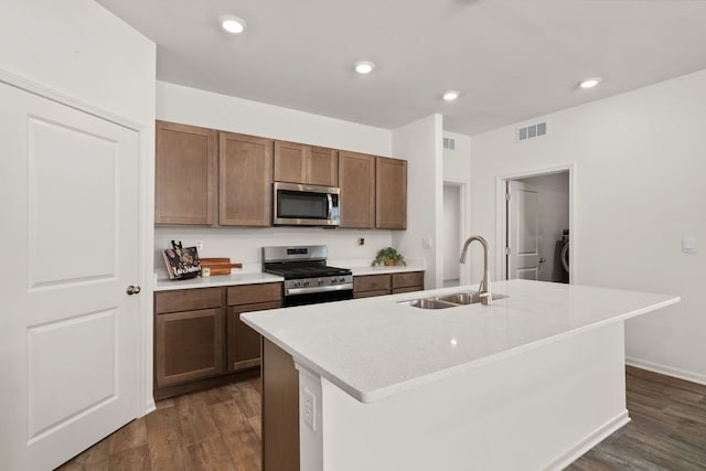 kitchen with a center island with sink, appliances with stainless steel finishes, and dark wood-type flooring