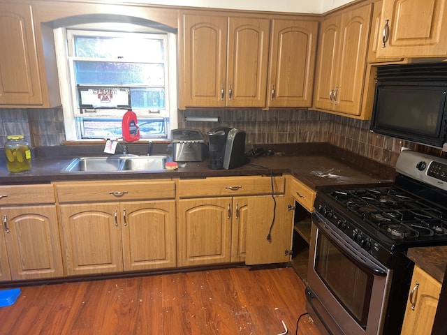 kitchen featuring sink, dark hardwood / wood-style flooring, stainless steel range with gas cooktop, and backsplash