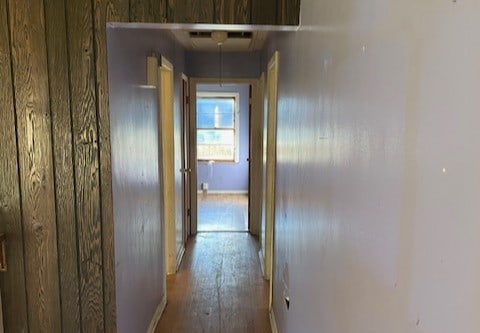 corridor featuring light hardwood / wood-style floors and wood walls