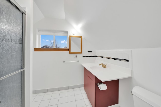 bathroom with tile patterned flooring, vaulted ceiling, vanity, and toilet