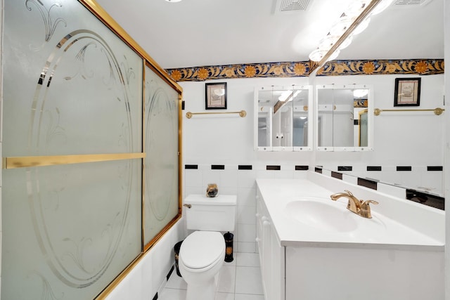 full bathroom with toilet, bath / shower combo with glass door, tile walls, vanity, and tile patterned flooring