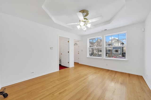 unfurnished bedroom featuring ceiling fan, a raised ceiling, and light hardwood / wood-style flooring